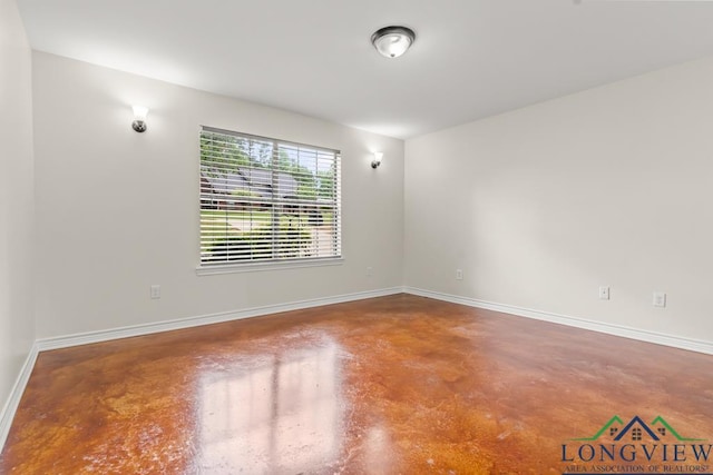 spare room with baseboards and finished concrete floors