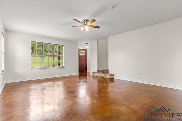 unfurnished room with ceiling fan, baseboards, and finished concrete floors
