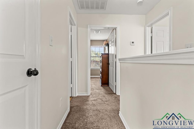 corridor with carpet floors, baseboards, and visible vents