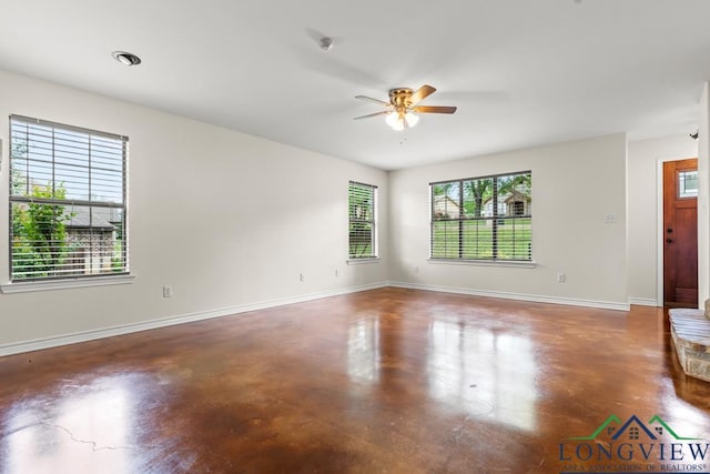 unfurnished living room with finished concrete flooring, baseboards, and a ceiling fan