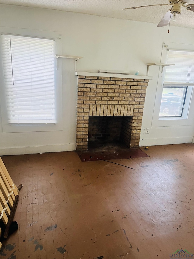 unfurnished living room with a brick fireplace, a textured ceiling, hardwood / wood-style flooring, and ceiling fan