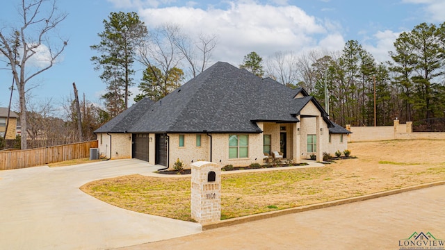 view of front of property featuring central AC, a garage, and a front lawn