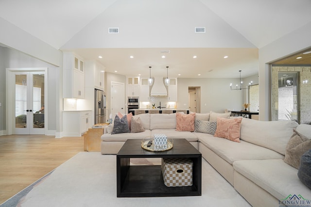 living room with french doors, sink, high vaulted ceiling, light hardwood / wood-style floors, and an inviting chandelier