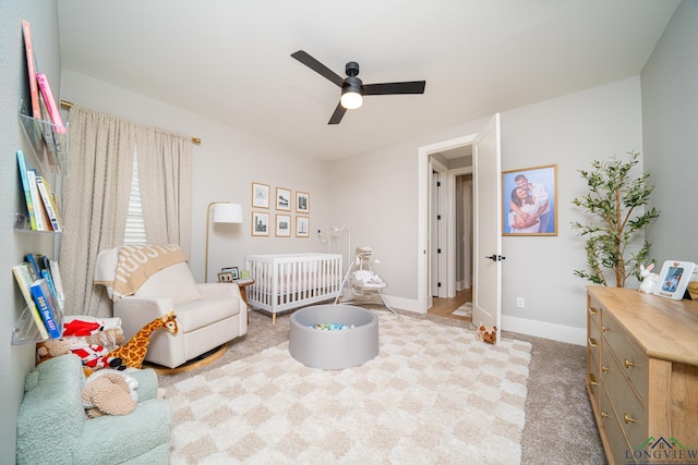 carpeted bedroom with ceiling fan and a nursery area