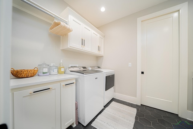 clothes washing area featuring cabinets, washing machine and dryer, and dark tile patterned floors