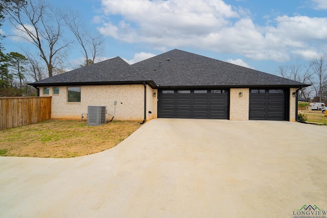 view of front of home with a front yard, central AC, and a garage