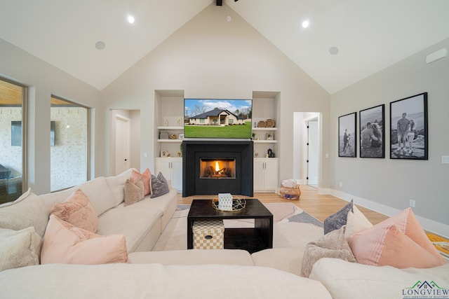 living room featuring built in shelves, light wood-type flooring, beam ceiling, and high vaulted ceiling