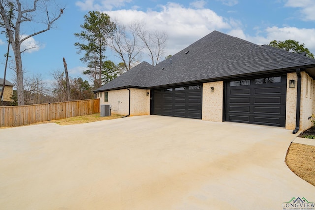 view of side of home with a garage and central AC