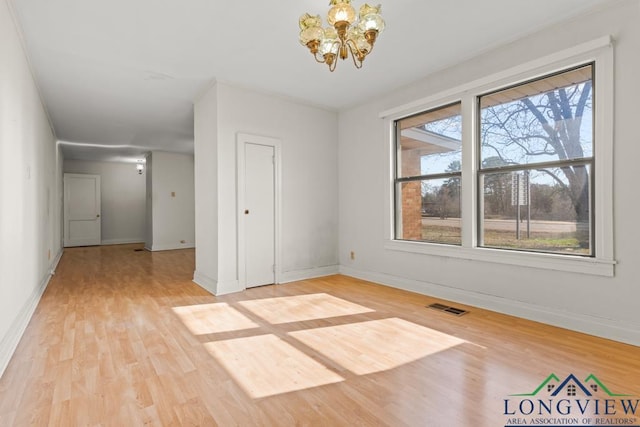 spare room with visible vents, baseboards, light wood-style floors, and an inviting chandelier