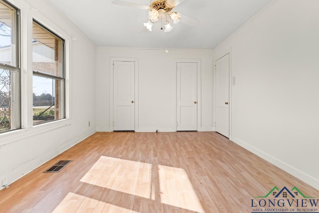 spare room with light wood-type flooring, visible vents, and baseboards