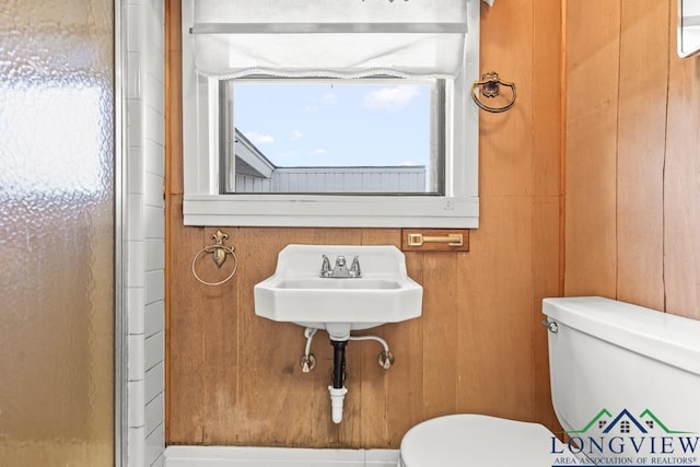 bathroom featuring an enclosed shower, toilet, and wood walls