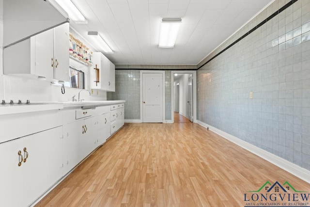 interior space with tile walls, wood finished floors, and a sink