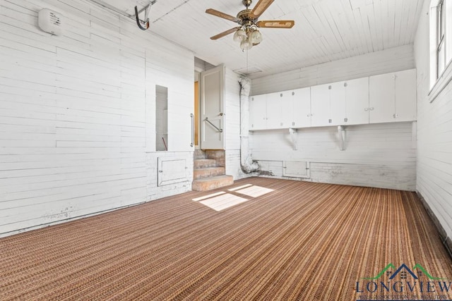 carpeted spare room with stairway and a ceiling fan