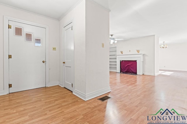 entryway with visible vents, crown molding, a fireplace with flush hearth, ceiling fan with notable chandelier, and light wood-style floors