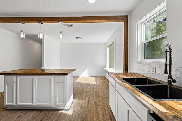 kitchen featuring dark wood-type flooring, sink, pendant lighting, butcher block countertops, and white cabinetry