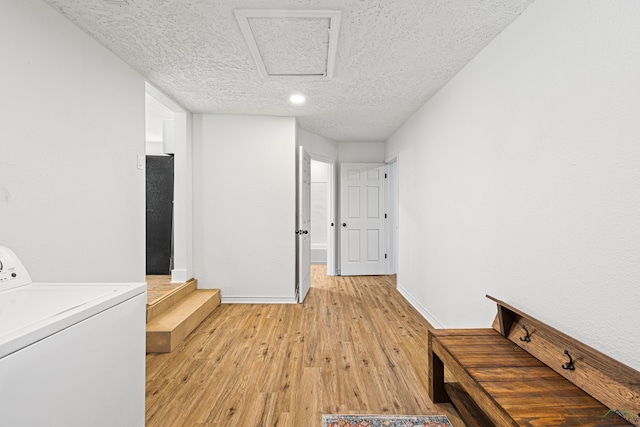 washroom featuring a textured ceiling, washer / clothes dryer, and light hardwood / wood-style floors