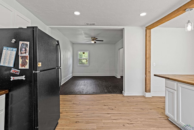 kitchen featuring pendant lighting, white cabinetry, black fridge, and light hardwood / wood-style floors