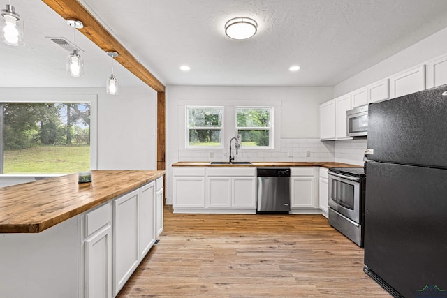 kitchen featuring wood counters, sink, hanging light fixtures, appliances with stainless steel finishes, and white cabinetry