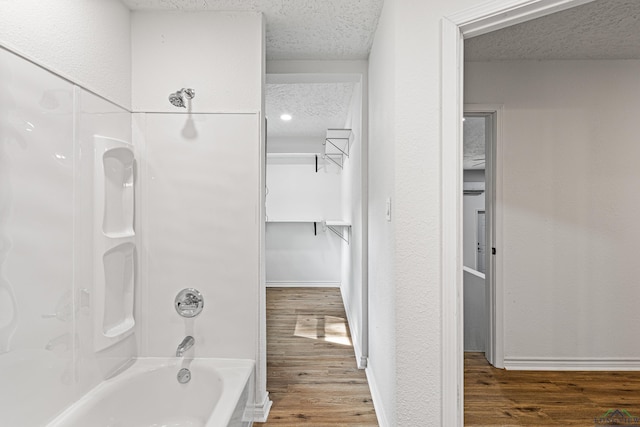 bathroom featuring hardwood / wood-style floors, a textured ceiling, and tub / shower combination