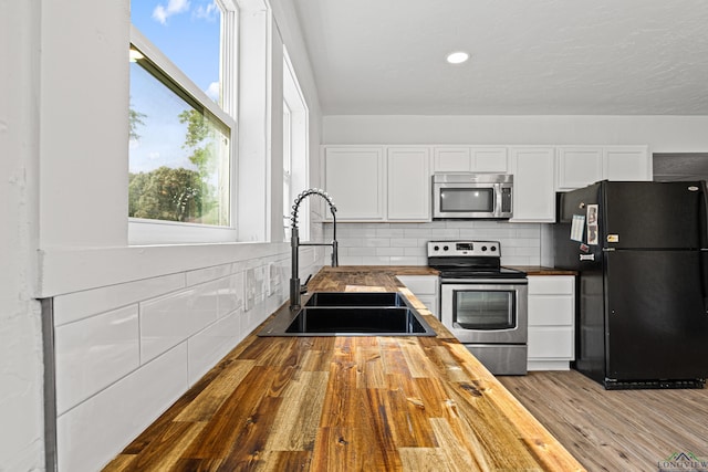 kitchen featuring white cabinets, appliances with stainless steel finishes, butcher block countertops, and sink