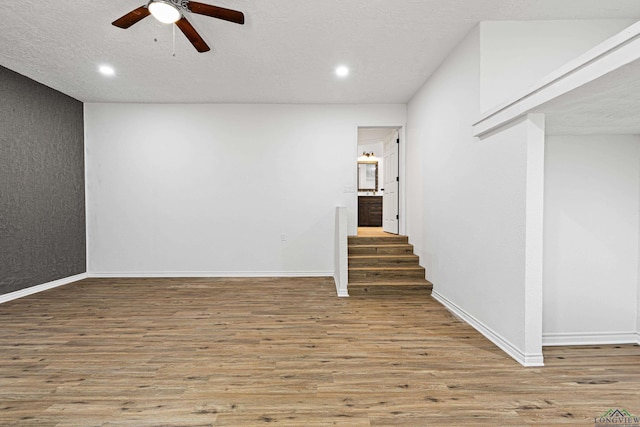 basement featuring hardwood / wood-style floors, a textured ceiling, and ceiling fan