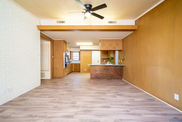 kitchen with brick wall, light hardwood / wood-style floors, kitchen peninsula, and wooden walls