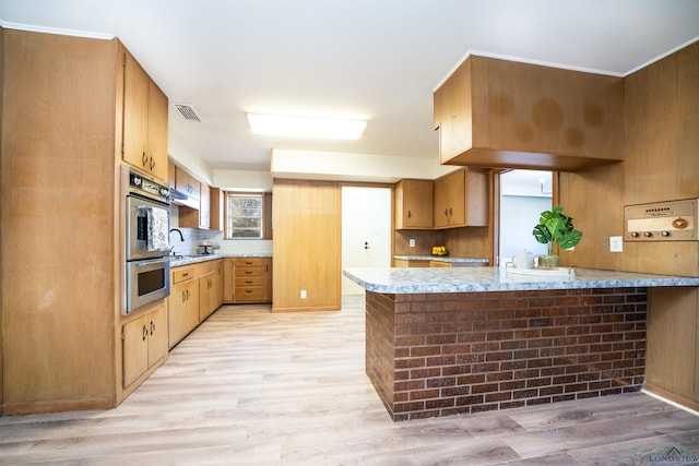 kitchen featuring decorative backsplash, light hardwood / wood-style flooring, kitchen peninsula, and stainless steel double oven