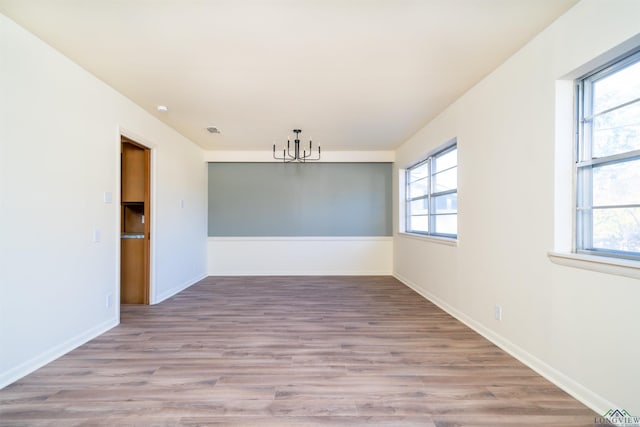 empty room featuring a chandelier and light hardwood / wood-style flooring