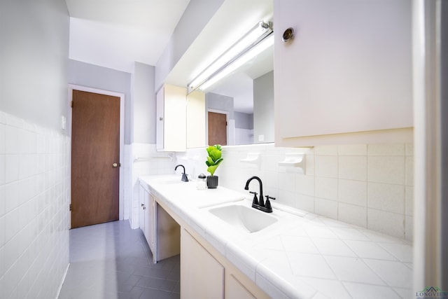 bathroom with tile walls, vanity, and tile patterned flooring