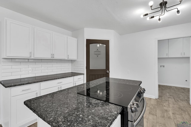 kitchen with white cabinetry, stainless steel electric stove, and decorative backsplash