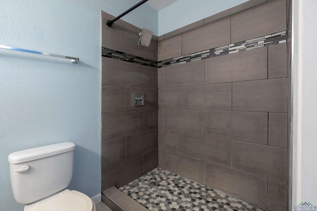 bathroom featuring toilet and a tile shower