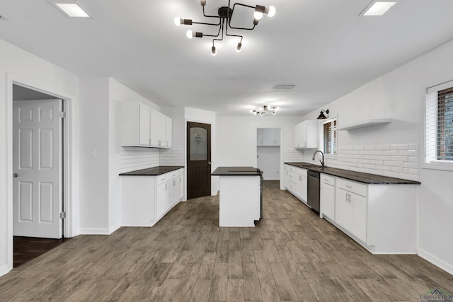 kitchen with a kitchen island, tasteful backsplash, white cabinetry, dishwasher, and hardwood / wood-style flooring