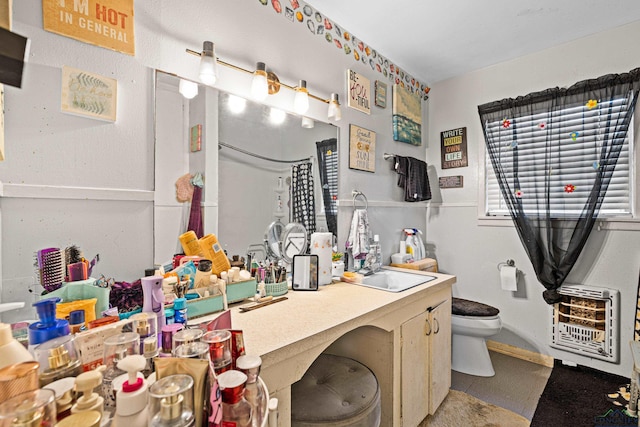 bathroom with heating unit, sink, and toilet