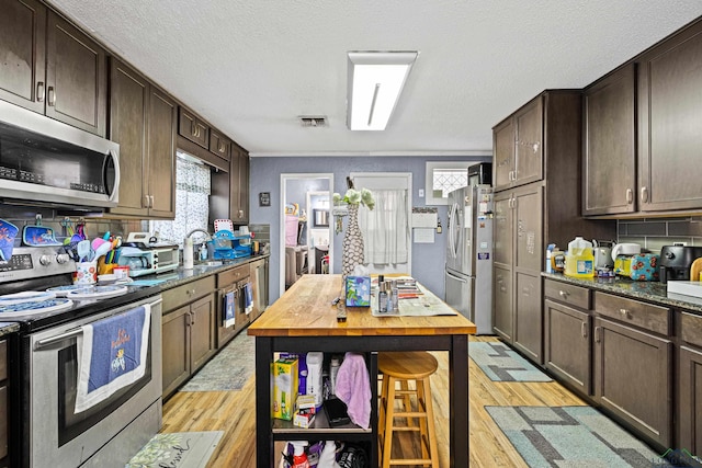 kitchen with decorative backsplash, light wood-type flooring, stainless steel appliances, and dark brown cabinetry