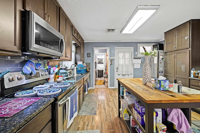 kitchen featuring stainless steel appliances, light hardwood / wood-style flooring, backsplash, a textured ceiling, and dark brown cabinets