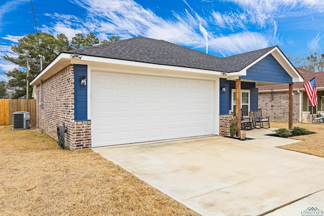 ranch-style home with a garage, a porch, a front yard, and central air condition unit