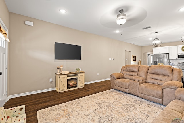 living room with dark wood-type flooring and ceiling fan