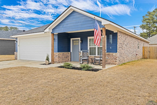 view of front of property featuring a porch, a garage, and a front lawn