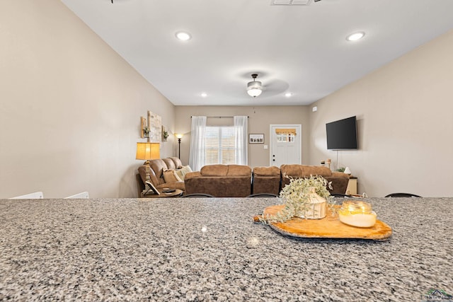 interior space with light stone counters and ceiling fan