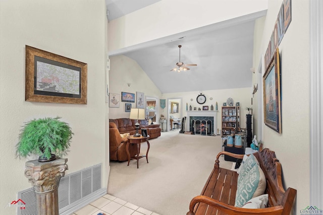 carpeted living room with a warm lit fireplace, ceiling fan, tile patterned flooring, and high vaulted ceiling