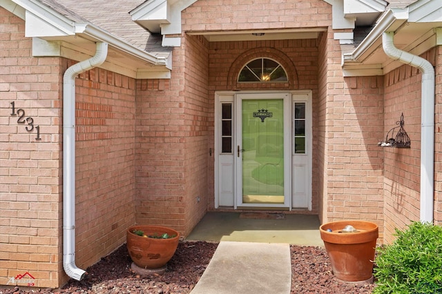 property entrance with brick siding and a shingled roof