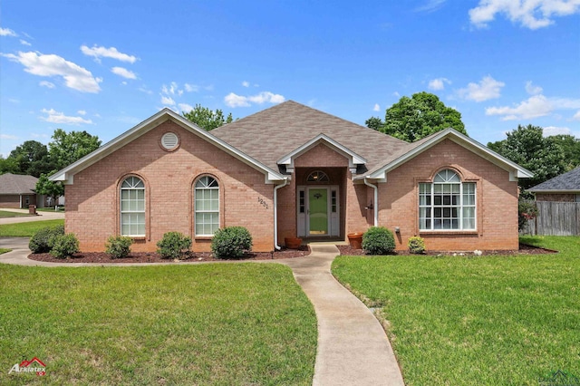 ranch-style house with brick siding, a front lawn, and roof with shingles