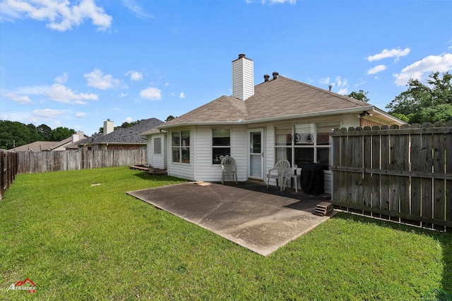 back of house with a lawn, a chimney, a fenced backyard, and a patio area