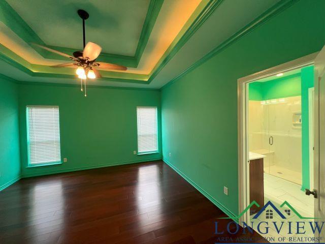 unfurnished room featuring dark hardwood / wood-style floors, ceiling fan, ornamental molding, and a tray ceiling