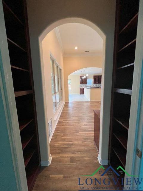 corridor featuring wood-type flooring and crown molding