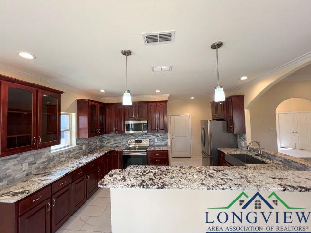 kitchen with appliances with stainless steel finishes, decorative light fixtures, sink, and decorative backsplash