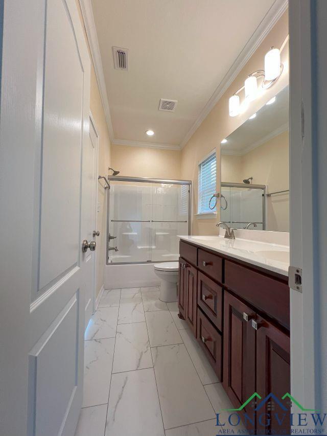 full bathroom featuring vanity, crown molding, shower / bath combination with glass door, and toilet