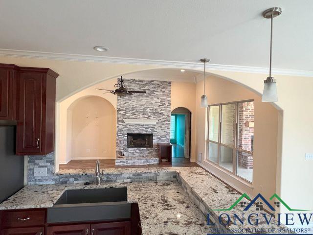 kitchen with a fireplace, decorative light fixtures, tasteful backsplash, ornamental molding, and ceiling fan