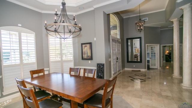 dining area featuring a chandelier, a towering ceiling, crown molding, and decorative columns