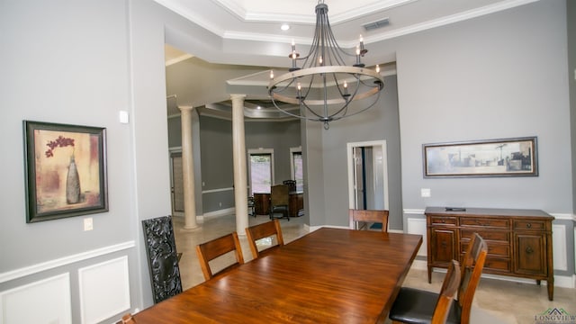 dining area featuring a notable chandelier, a raised ceiling, ornate columns, and crown molding